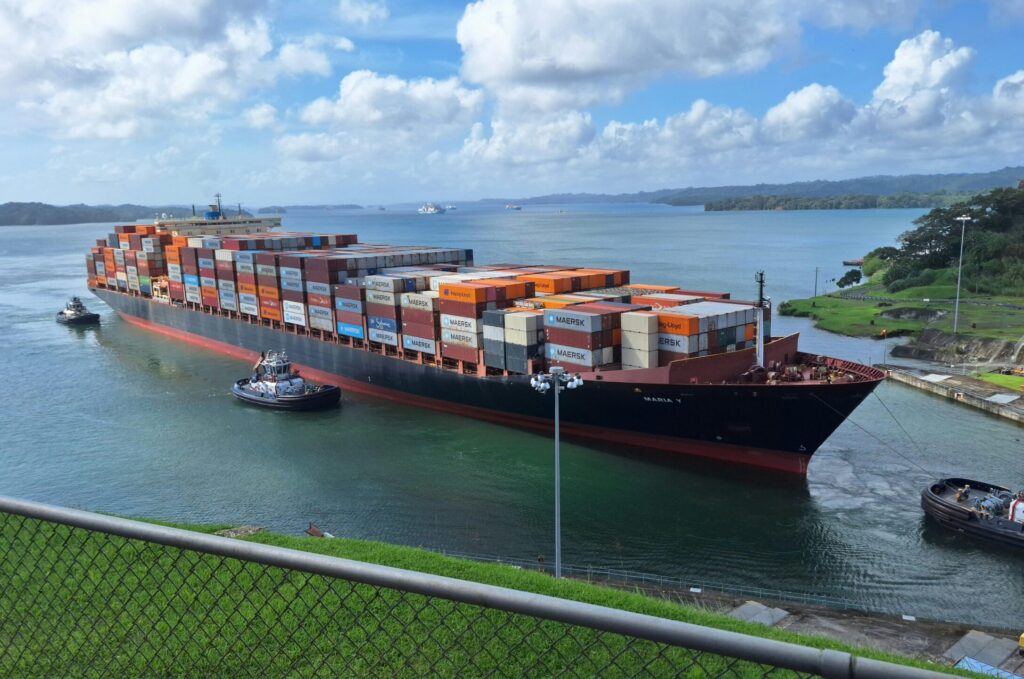Large container ship maneuvered by tugboats through the Panama Canal