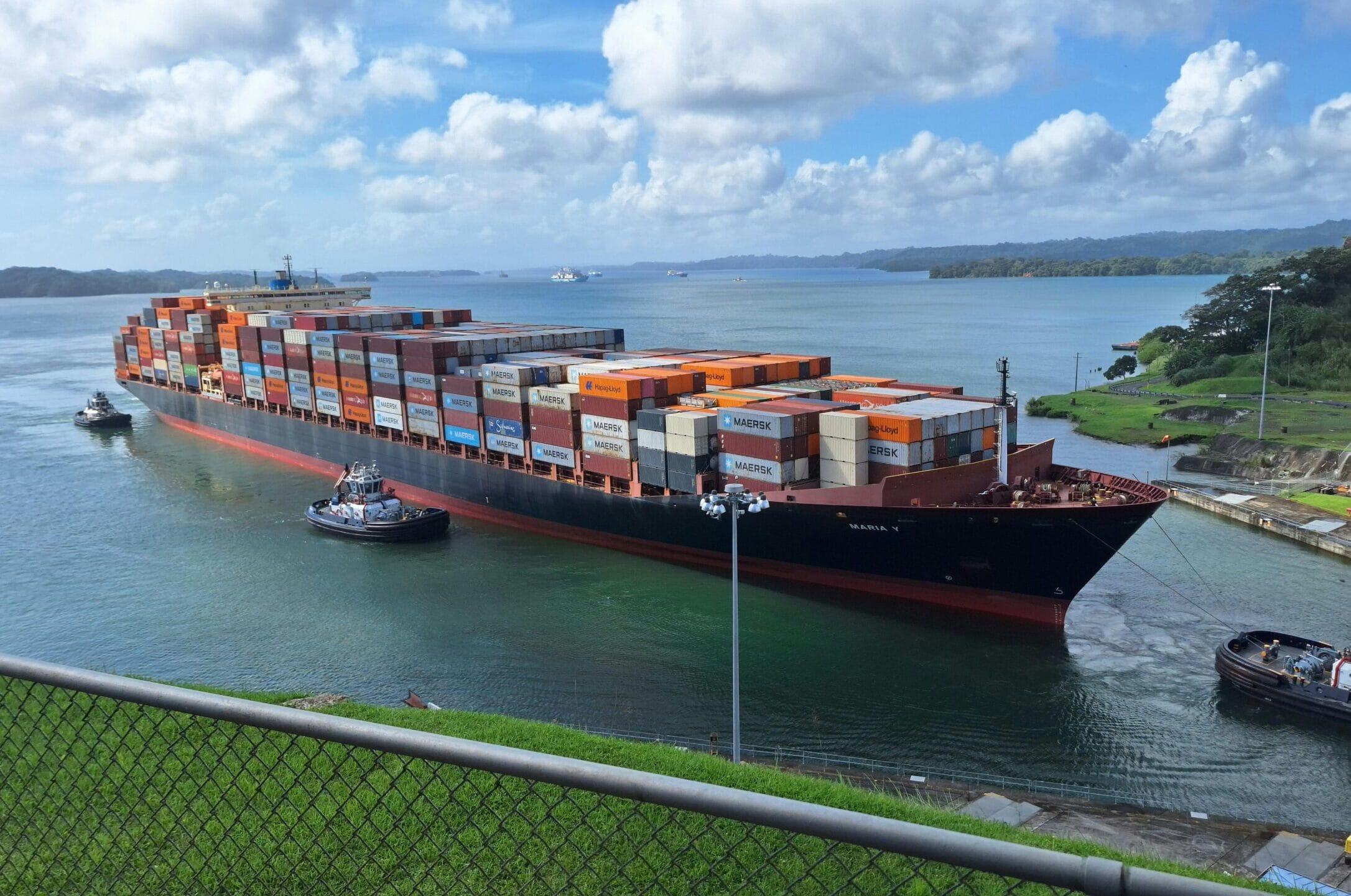 Large container ship maneuvered by tugboats through the Panama Canal
